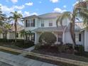 Two-story light green house with a white door, landscaping, and a metal roof on a sunny day at 322 Ibisview Ln, Apollo Beach, FL 33572