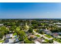 Expansive aerial view of a home in a lush, green neighborhood with a glimpse of the ocean and city skyline at 4510 Helena Ne St, St Petersburg, FL 33703