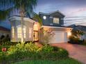 Charming two-story home boasts a well-manicured lawn and a paver driveway leading to a two-car garage at 5011 Sandy Brook Cir, Wimauma, FL 33598