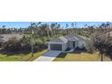 Single-story house with a gray roof, driveway, and a grassy yard at 211 Australian Dr, Rotonda West, FL 33947