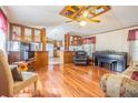 Open-concept living room with wood floors, ceiling fan, and a partial view of the kitchen at 4635 Orange Blossom Dr, Zephyrhills, FL 33542