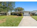 Ranch-style home with a gray exterior, attached garage, and lush lawn at 1993 59Th N Way, St Petersburg, FL 33710