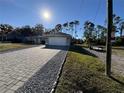 Home's exterior showcases a paved driveway leading to a two-car garage and a spacious yard at 3087 Seth Rd, North Port, FL 34288