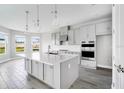Modern kitchen features an island with pendant lighting, ample storage, stainless appliances, and sleek countertops at 1979 Longliner Loop, Wesley Chapel, FL 33543