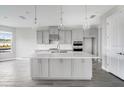 Modern kitchen features an island with pendant lighting, ample storage, stainless appliances, and sleek countertops at 1979 Longliner Loop, Wesley Chapel, FL 33543