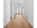 Bright hallway featuring hardwood floors and decorative lighting, leading to double doors at 34 Concord Dr, Dunedin, FL 34698