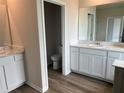 Bathroom with double sinks, granite counters, white cabinets, framed mirror, and wooden floors at 16033 7Th E Ave, Bradenton, FL 34212