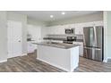 Modern kitchen with white cabinets, stainless steel appliances, and an island with seating at 7703 Peace Lily Ave, Wesley Chapel, FL 33545