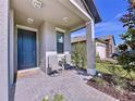 Front porch with gray pavers, two chairs, and potted plants at 21590 Violet Periwinkle Dr, Land O Lakes, FL 34637