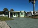 Front view of a charming light green manufactured home with a spacious driveway at 35127 Danny Dr, Zephyrhills, FL 33541