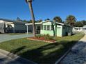 Side view of a light green manufactured home showcasing a well-maintained lawn at 35127 Danny Dr, Zephyrhills, FL 33541