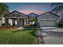 Attractive one-story home with stone accents and a two-car garage at dusk at 8144 Sequester Loop, Land O Lakes, FL 34637