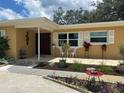 Inviting front entrance with a tiled porch, white chairs, and decorative flower planters, adding charm and curb appeal at 209 Westwinds Dr, Palm Harbor, FL 34683