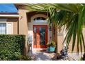 Inviting front door entrance with orange door and landscaping at 528 Painted Leaf Dr, Brooksville, FL 34604