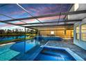 Stunning pool and spa with covered patio overlooking a lake at sunset at 11807 Cross Vine Dr, Riverview, FL 33579