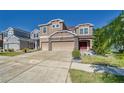 Two-story house with a large beige exterior, stone accents, and a three-car garage at 10439 Waterstone Dr, Riverview, FL 33578