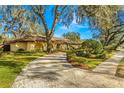 Curved driveway leading to a ranch home nestled among large trees at 1116 N Riverhills Dr, Temple Terrace, FL 33617
