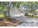 Paver driveway leading to a two-car garage, enhanced by mature trees for a shaded entrance to the residence at 14324 Moon Flower Dr, Tampa, FL 33626