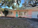 Pink house with teal door and large windows, situated on a grassy lot at 6035 Grand Blvd, New Port Richey, FL 34652