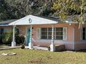 Quaint pink house with white trim and teal columns, showcasing a charming facade at 6035 Grand Blvd, New Port Richey, FL 34652