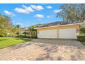 Tan house with a three car garage and well manicured lawn at 615 Westfield Ct, Dunedin, FL 34698