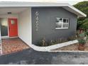 Mid-century modern home with a vibrant orange door at 6452 1St Palm Pt, St Pete Beach, FL 33706