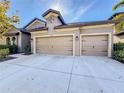 Tan three-car garage house with landscaping at 11409 Drifting Leaf Dr, Riverview, FL 33579