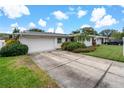 Front view of a ranch house with a white garage door and landscaping at 1480 Santa Monica Dr, Dunedin, FL 34698