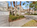 Partial view of tan townhome with white garage door and lush landscaping at 14433 Mirabelle Vista Cir, Tampa, FL 33626