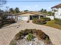 Tan house with white garage door and landscaped yard, paver driveway at 10208 Tarpon Dr, Treasure Island, FL 33706