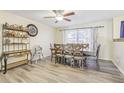 Bright dining room with wood-look flooring, a ceiling fan, large window, and a dining table with seating for six at 3407 King George Ln, Seffner, FL 33584