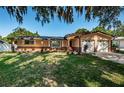 Ranch style home with two car garage and lush lawn at 1201 Kapok Cir, Clearwater, FL 33759