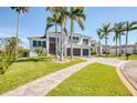 Two-story home with a well-manicured lawn, palm trees, and large driveway, set against a clear blue sky at 5951 Bay Dr, Gulfport, FL 33707