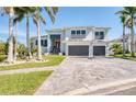 Beautiful two-story home featuring a manicured lawn, brick driveway, and lush palm trees at 5951 Bay Dr, Gulfport, FL 33707