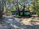 Light green house with a brown roof, surrounded by mature trees and a gravel driveway at 12308 N 52Nd St, Temple Terrace, FL 33617