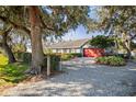 Home with red door and gravel driveway, surrounded by landscaping at 3111 Lewis Rd, Dover, FL 33527
