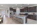 Modern kitchen with dark cabinetry, granite countertops, and an island with seating at 10725 Tippecanoe Pl, Parrish, FL 34219