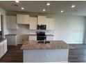 Modern kitchen featuring white cabinets, granite countertops, stainless steel appliances, and a central island at 16025 7Th E Ave, Bradenton, FL 34212