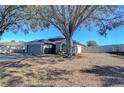 Gray house with a two-car garage and a large driveway, surrounded by mature trees at 1732 Tinker Dr, Lutz, FL 33559