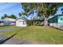 Front view of a yellow house with a single-car garage and spacious yard at 2609 Meadowbrook Dr, Palm Harbor, FL 34684