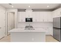 A modern kitchen with white cabinets, stainless steel appliances, an island, and a pantry at 18475 Green Garden Ct, Venice, FL 34293