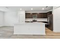Modern kitchen featuring stainless steel appliances, dark wood cabinetry, an island and light countertops at 10524 Hidden Banks Gln, Parrish, FL 34219