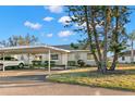 View of a quaint light blue home with a carport and healthy, green landscaping at 2232 Greenwich Dr # 56, Sun City Center, FL 33573
