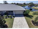 Aerial view of a single-story home with paver driveway, mature landscaping and lake view at 1506 Bentwood Dr, Sun City Center, FL 33573