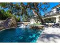 Backyard pool with a slide, a hot tub, lounge chairs in the pool and a fire pit at 4518 W Rosemere Rd, Tampa, FL 33609
