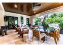 A covered patio offers a lounge area with a ceiling fan, a dining area, and views of the beautiful yard at 4518 W Rosemere Rd, Tampa, FL 33609