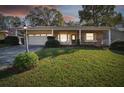 Evening view of a ranch home with stone accents and a landscaped yard at 6474 Pine Meadows Dr, Spring Hill, FL 34606