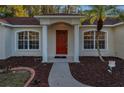 Front entrance with red door, columns, and landscaped walkway at 9800 Mendel Dr, New Port Richey, FL 34654