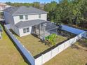 Two-story house with a fenced backyard, screened patio, and open grassy area at 10703 Aldo Moro Dr, Wimauma, FL 33598