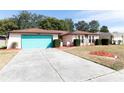 Ranch style home with teal garage door and well-manicured lawn at 12609 Shadow Ridge Blvd, Hudson, FL 34669